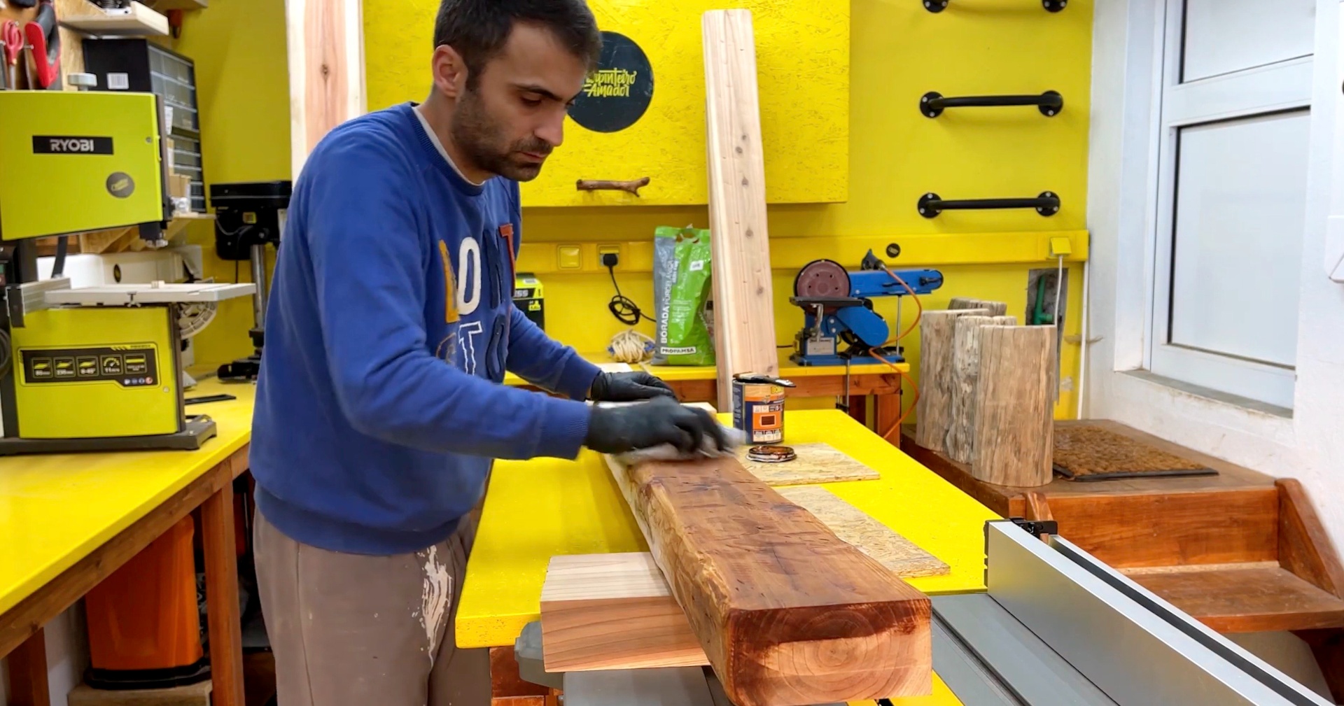 Rui in his workshop, applying finish to a slab of wood